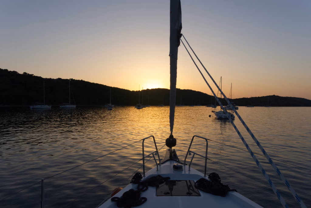 Sailboat anchored in a quiet bay around Mljet or Lastovo, no crowd, sunset light.